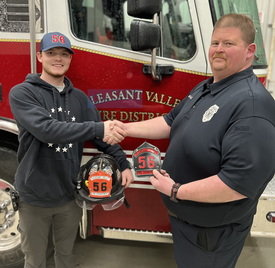 Captain Ken Wallace (R) performing the traditional probationary helmet shield swap with Firefighter Jonathan Long (L). 